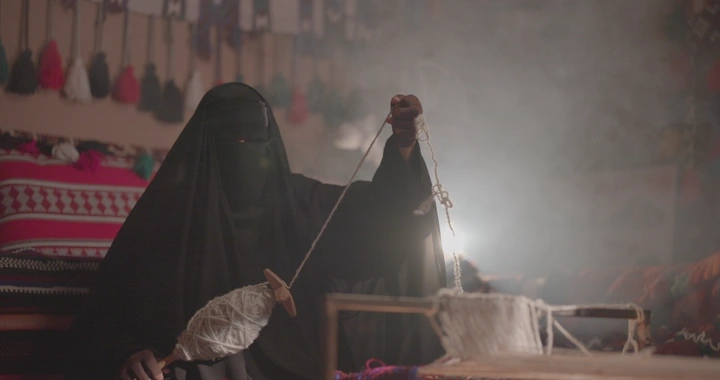 امرأة تنسج السدو في ورشة تقليدية، لقطة داخلية.