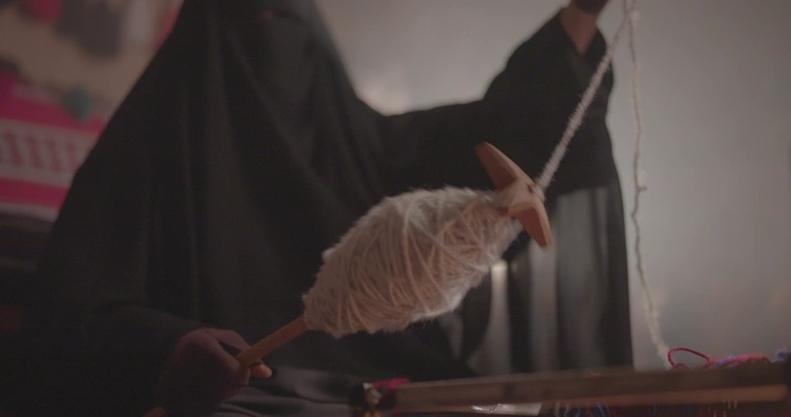 امرأة تغزل السدو في مكان مغلق، لقطة قريبة.