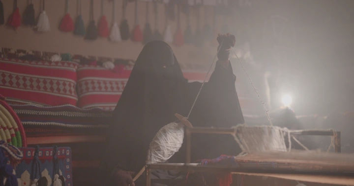 امرأة تنسج السدو في غرفة تقليدية، لقطة ضبابية.