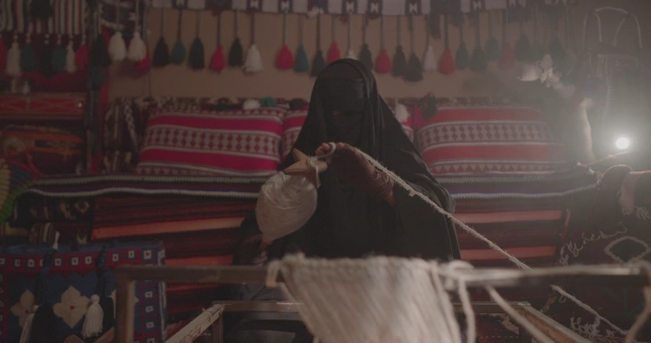 امرأة تنسج السدو في غرفة تقليدية، لقطة داخلية.