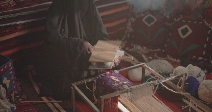 امرأة تنسج السدو في خيمة تقليدية، لقطة داخلية.
