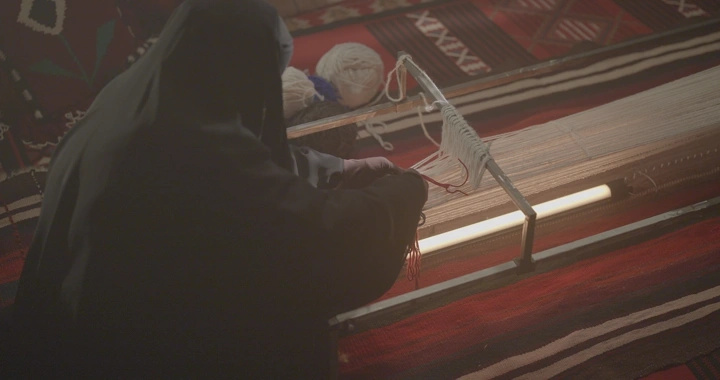 امرأة تنسج على نول سدو تقليدي، لقطة داخلية.