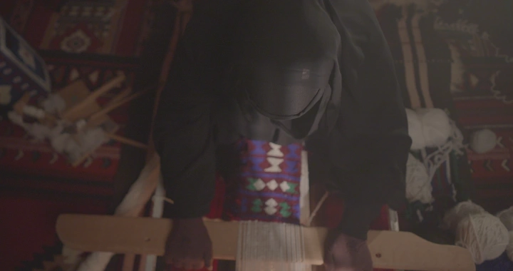 امرأة تعمل على نول السدو في غرفة تقليدية، لقطة علوية.