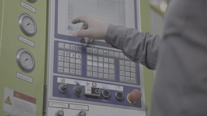 يد تتحكم في لوحة تحكم صناعية، لقطة قريبة.