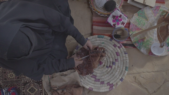 امرأة تصنع قربة تقليدية على الأرض، لقطة من الأعلى.