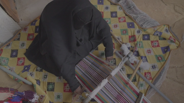 امرأة تنسج سدو تقليدي على نول، لقطة علوية.
