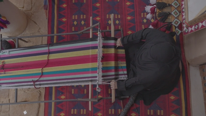 امرأة تنسج سدو تقليدي في الداخل، لقطة علوية.