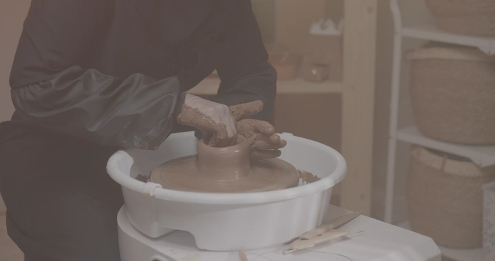 صانعة فخار تعمل على عجلة في ورشة، لقطة مقربة.
