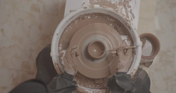 صانعة فخار تعمل على عجلة دوارة، لقطة من الأعلى.