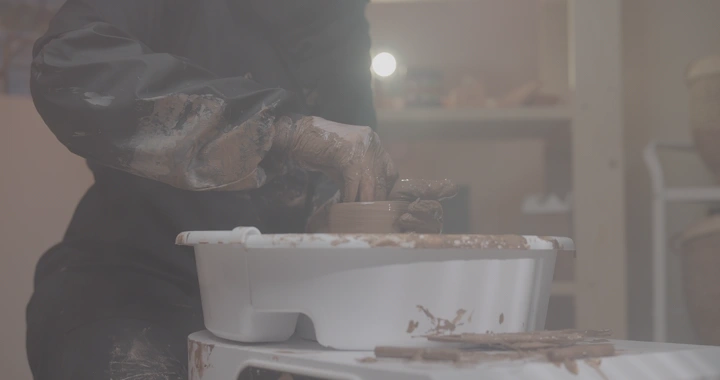 صانعة فخار تعمل على عجلة في ورشة، لقطة قريبة.