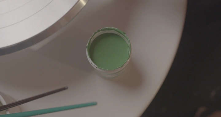 علبة طلاء أخضر على طاولة بيضاء، لقطة علوية.