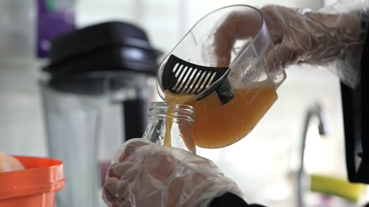 صب عصير برتقال في زجاجة، لقطة مقربة.