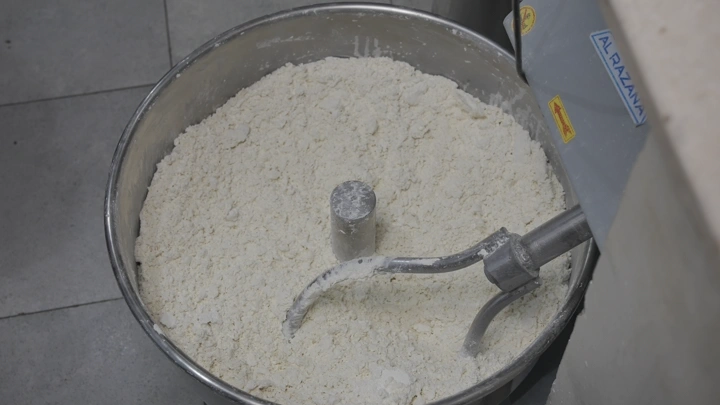 عجين في خلاط معدني في مطبخ صناعي، لقطة مقربة.