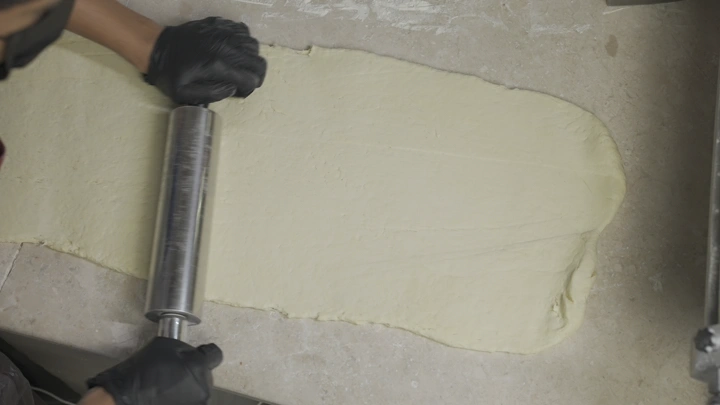 فرد العجين على سطح رخامي، لقطة علوية.