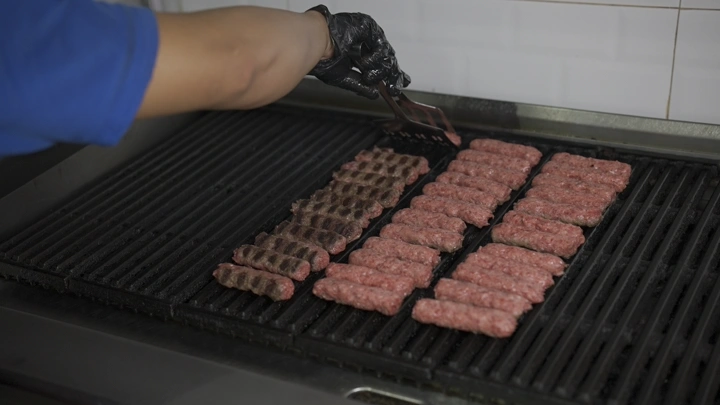 شخص يشوي كباب على شواية في مطبخ، لقطة قريبة.