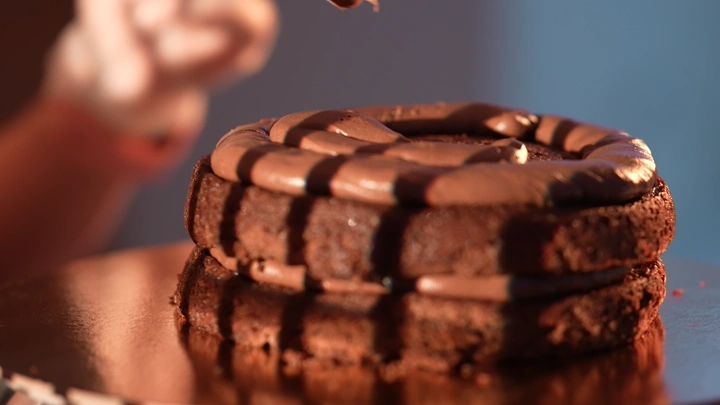 كيكة شوكولاتة مزينة بالكريمة في مطبخ، لقطة مقربة.