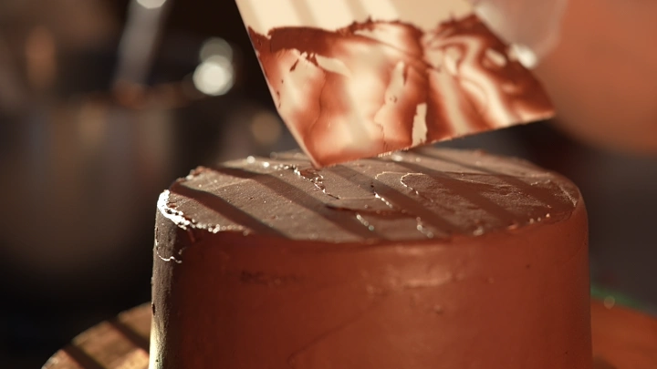 كيكة شوكولاتة يتم تزيينها بالشوكولاتة، لقطة مقربة.