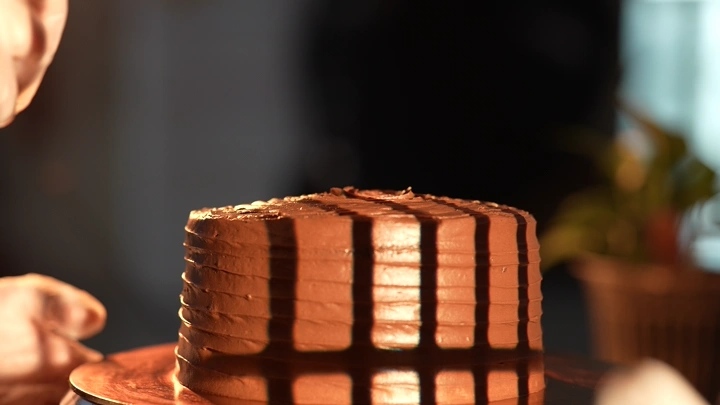 تزيين كيكة شوكولاتة على طاولة في ضوء الشمس، لقطة مقربة.