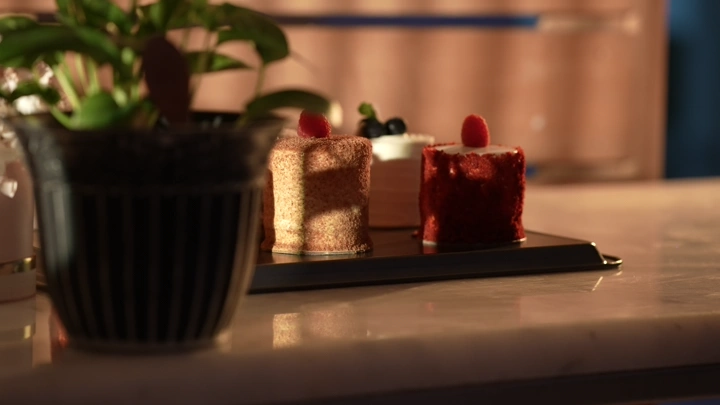 قطع كيك على طاولة مع نبات، إضاءة دافئة.