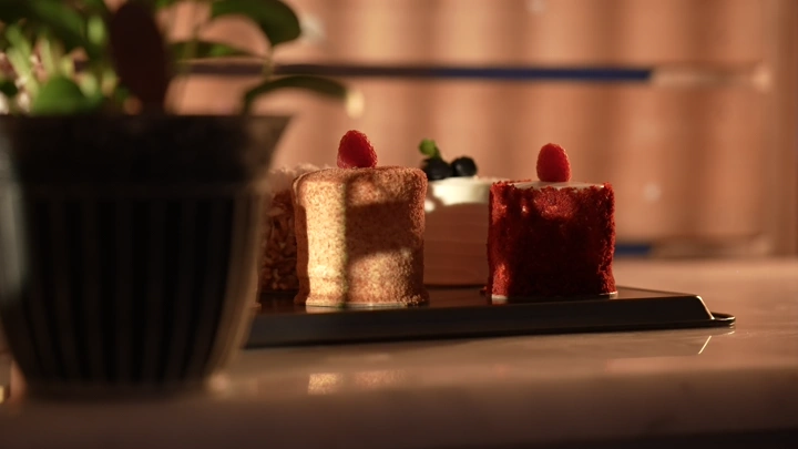 قطع كيك مزينة بالتوت على طاولة، إضاءة دافئة.