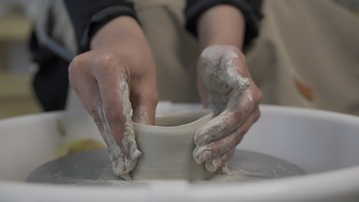 أيدي تصنع الفخار على عجلة دوارة، لقطة مقربة.