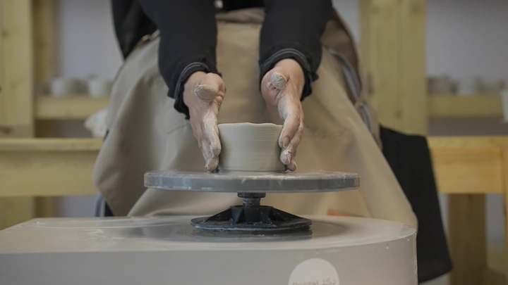 صانع فخار يعمل على عجلة في ورشة، لقطة مقربة.