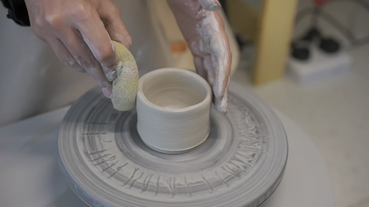 صناعة الفخار على عجلة دوارة في ورشة عمل، لقطة مقربة.