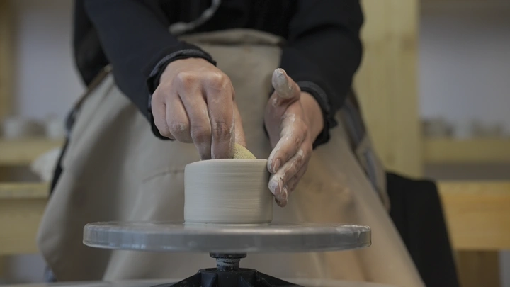 صانعة فخار تعمل على عجلة دوارة، لقطة مقربة.