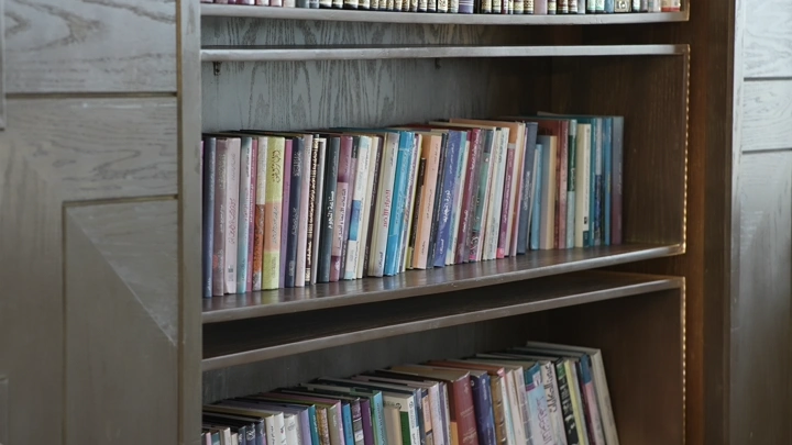 رف كتب مليء بالكتب في مكتبة، لقطة قريبة.