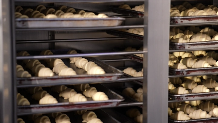 كرواسون غير مخبوز على رفوف في مخبز، لقطة قريبة.