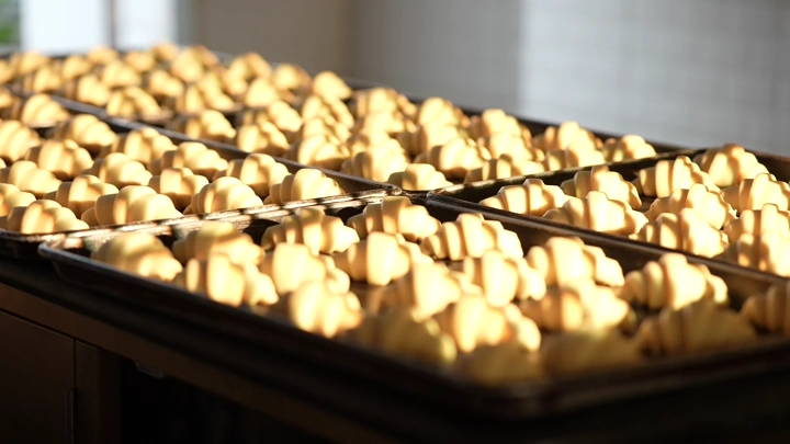 صواني كرواسان في فرن مخبز، لقطة قريبة.