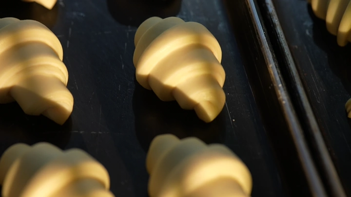 كرواسون غير مخبوز على صينية خبز، إضاءة طبيعية.