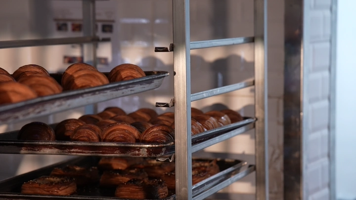 كرواسون طازج على رفوف معدنية في مخبز، لقطة داخلية.