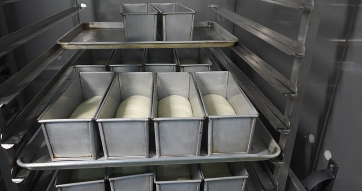 عجينة خبز في قوالب معدنية داخل فرن، لقطة قريبة.