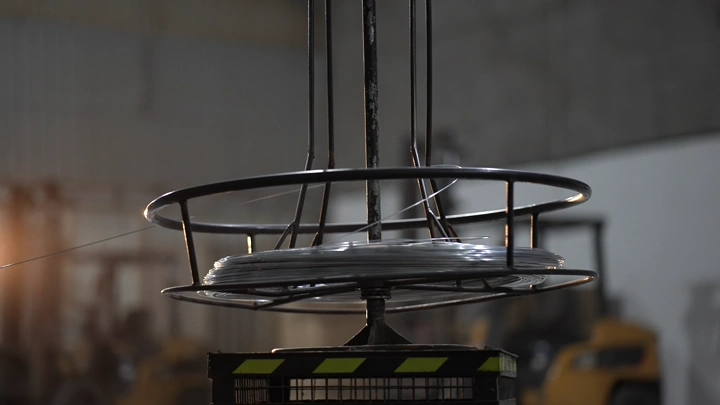 رافعة تحمل لفائف معدنية في مصنع حديد، لقطة داخلية.