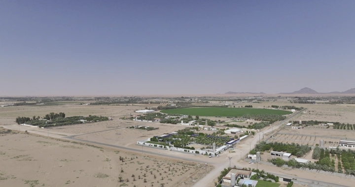 مزرعة في منطقة صحراوية تحت سماء زرقاء، لقطة جوية.