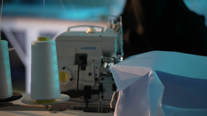 ماكينة خياطة مع قماش في ورشة عمل، لقطة قريبة.