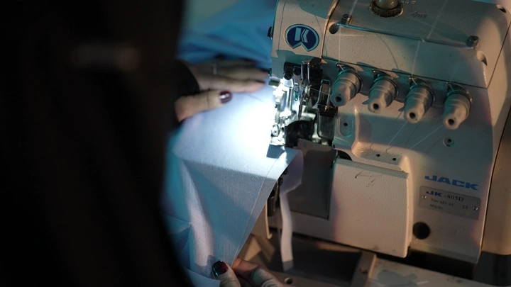 آلة خياطة تعمل على قماش تحت إضاءة ساطعة، لقطة مقربة.
