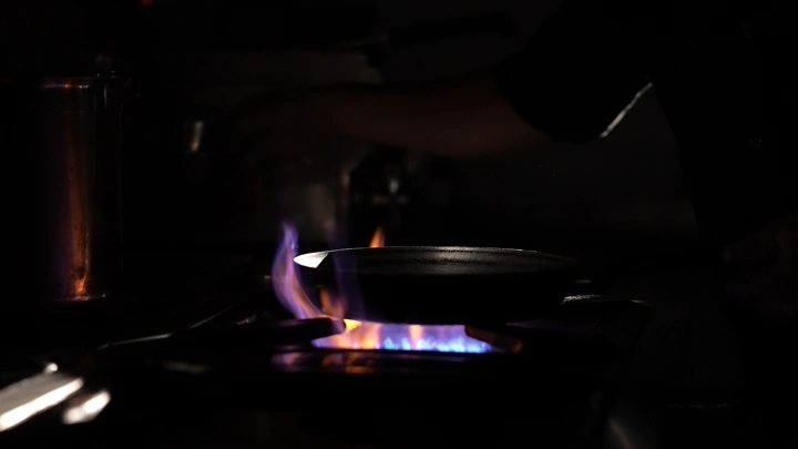 مقلاة على نار موقد في مطبخ مظلم، لقطة مقربة.