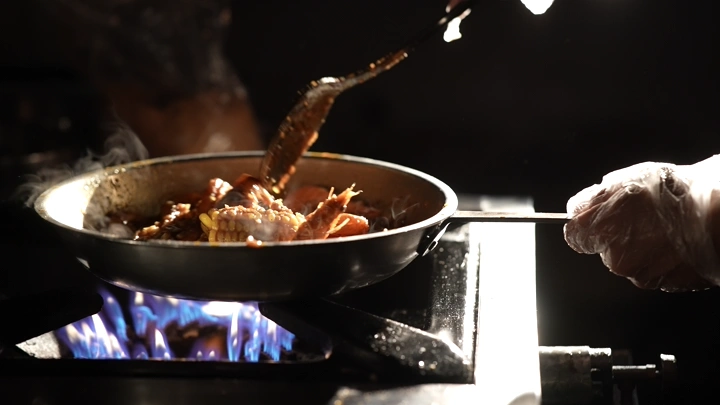 طهي الروبيان في مقلاة على نار مشتعلة، لقطة قريبة.