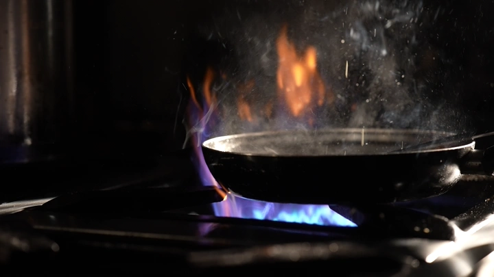 مقلاة على نار مشتعلة في مطبخ، لقطة قريبة.