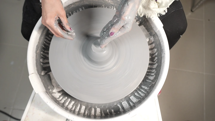 فنان تشكل الطين على عجلة الفخار، لقطة علوية.