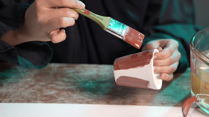 شخص يلون كوبًا بفرشاة في الداخل، لقطة مقربة.