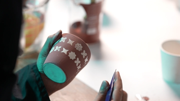 شخص يزين فخارًا في ورشة عمل، لقطة مقربة.