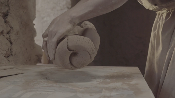 يد تشكل الطين على طاولة، لقطة قريبة.