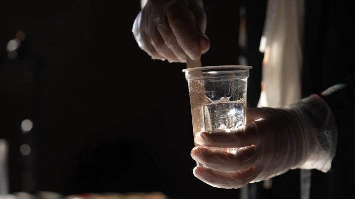 شخص يخلط مادة الريزن في كوب بلاستيكي، لقطة مقربة.