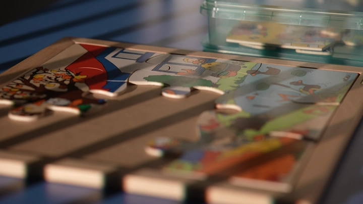 قطع أحجية على طاولة مع طفل يحلها، لقطة قريبة.