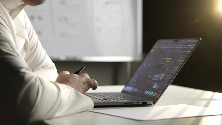 شخص يعمل على كمبيوتر محمول في مكتب، لقطة جانبية.