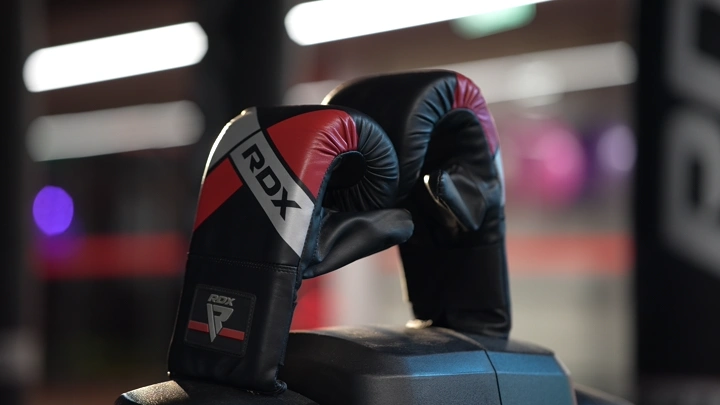 قفازات ملاكمة على حقيبة تدريب في صالة رياضية، لقطة قريبة.