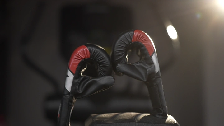 قفازات ملاكمة على كرسي في صالة رياضية، لقطة قريبة.